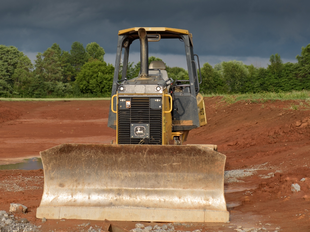 grader construction equipment at building site dark clouds photo