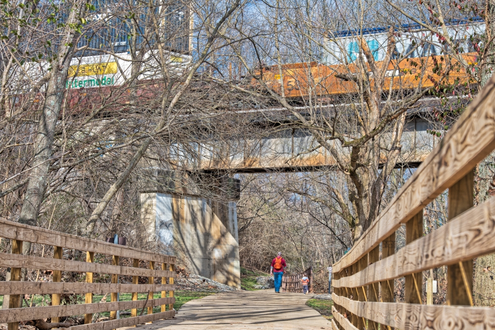 train traveling over bridge with people walking under 85022E