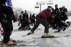  An adaptive skier receives assistance at the base of a ski lift