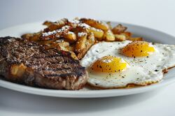 breakfast with two fried eggs steak fried potato
