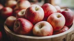 Red apples stacked in a rustic wooden bow