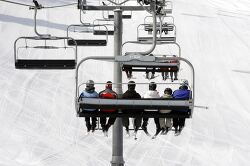 Skiers ride up a mountain on a chairlift
