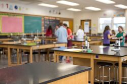 students in a school lab with tables and stools set up for learning