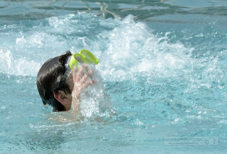 child wearing yellow goggles playing in a pool