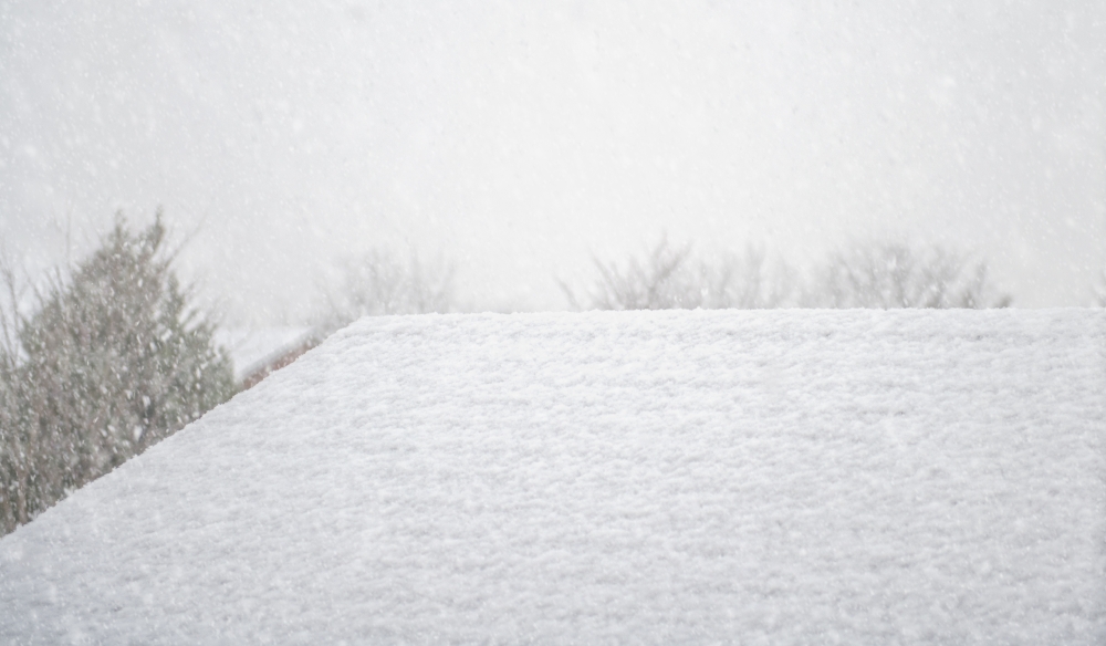 snow accumulating on roof of house