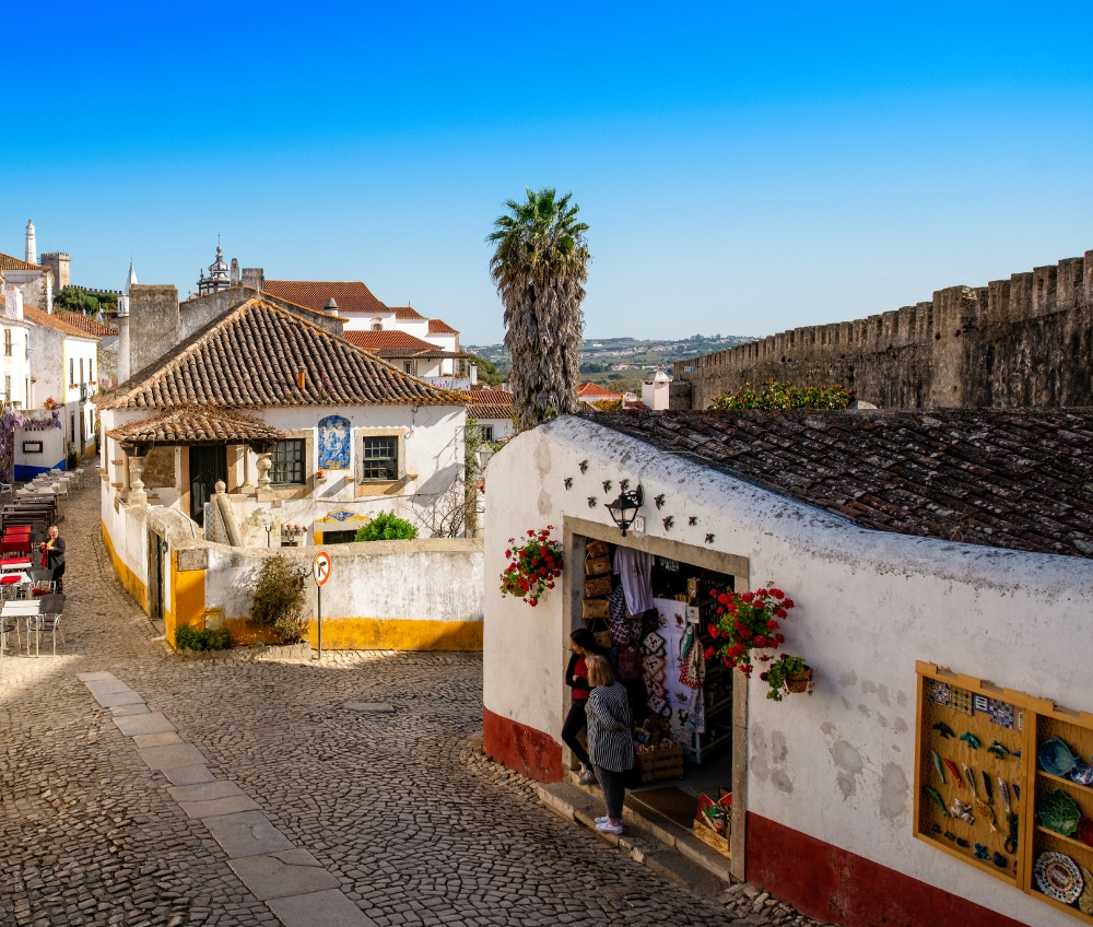 white washed building cobble stone street obidos portugal