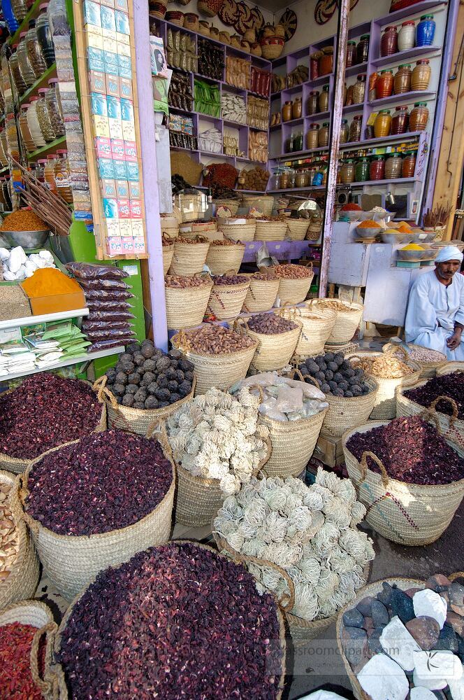 In a bustling market in Aswan Egypt baskets overflowing with various dried herbs spices and other natural products are on display A vendor sits nearby showcasing local goods