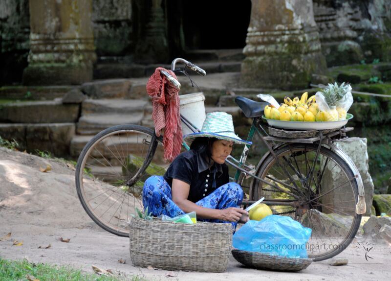 In the vibrant surroundings of Siem Reap near Angkor Wat a local vendor prepares fresh produce while seated beside her bicycle. The tranquil atmosphere highlights cultural traditions in everyday life.