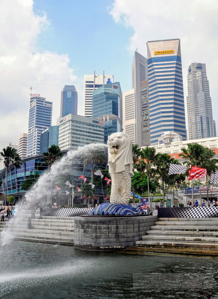 This landmark sculpture of the Merlion spouts water against a backdrop of modern skyscrapers, showcasing Singapore