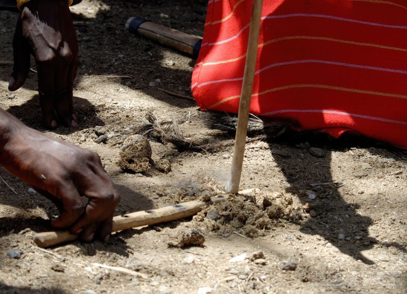 A Samburu villager skillfully demonstrates how to create fire using a wooden stick and dung on the ground This technique is a vital part of the Samburu culture in Kenya showcasing their resourcefulness and traditional practices