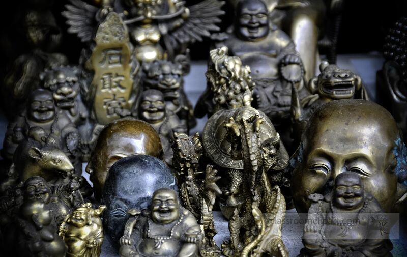 A vibrant array of bronze Buddha figurines fills the display at a market in Singapore. Each piece showcases intricate designs and varying styles, attracting collectors and spiritual seekers alike.